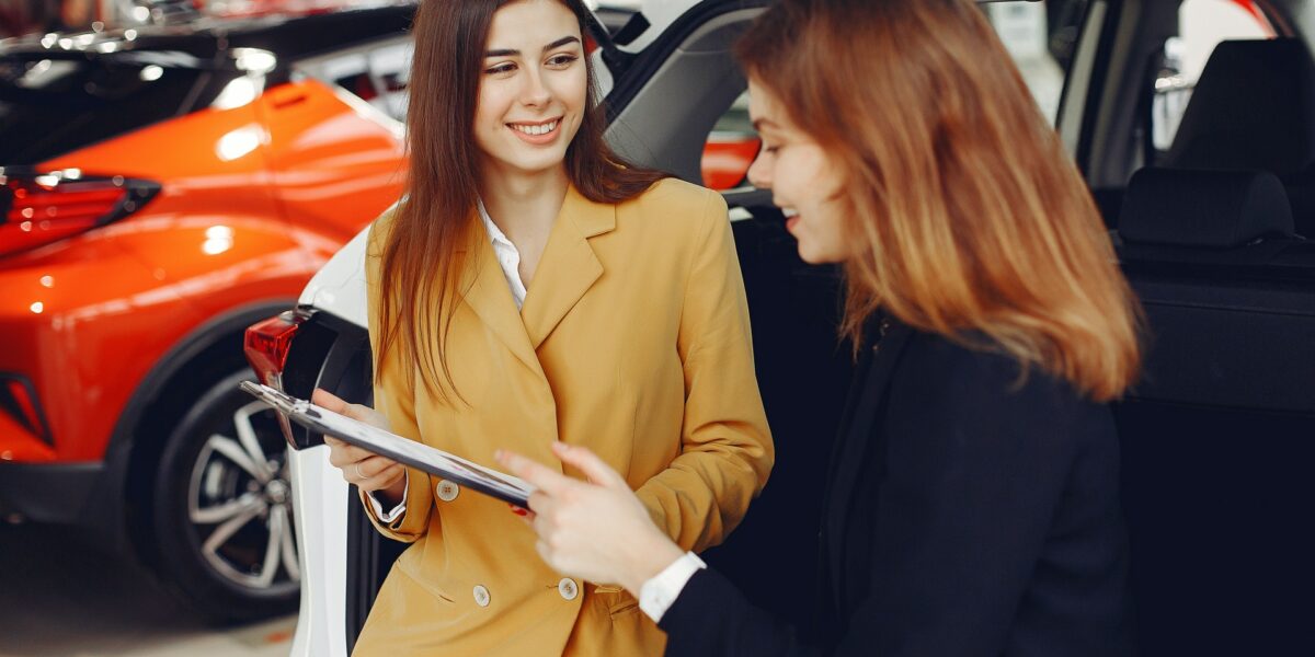 Woman shopping for new car at dealership smiling at salesperson.