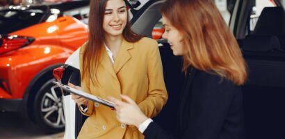 Woman shopping for new car at dealership smiling at salesperson.