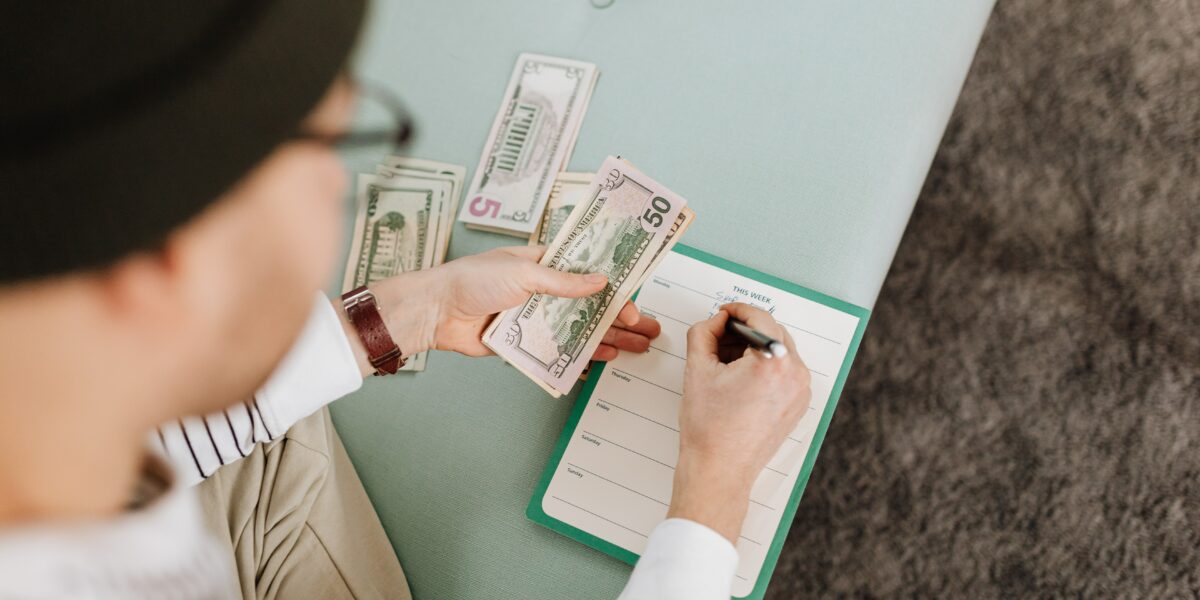 Young man counts money and fills in his budget.