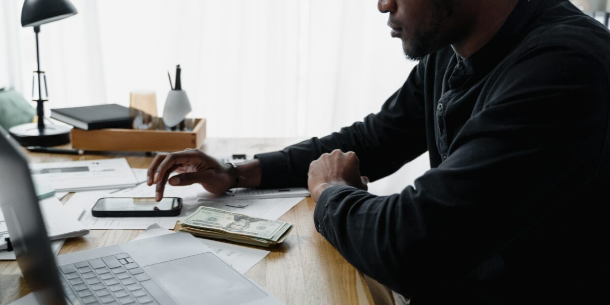 A Man in Black Long Sleeves Using a Calculator